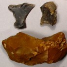 Strike-a-light stones for making fire, from the Daniels house. The black and gray ones were made from English flint ship-ballast cobbles, and the bottom one was made from a 2,000 year-old Native American stone tool of red Pennsylvania jasper stone. It may have been found by members of the Daniels family while they were working their fields - AHS, Inc., Storrs