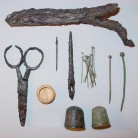 Sewing items from the Sprague house including scissors, needles, straight pins, thimbles, and a bone cap from a needle case. Colonial families made most of their own clothing - AHS, Inc., Storrs