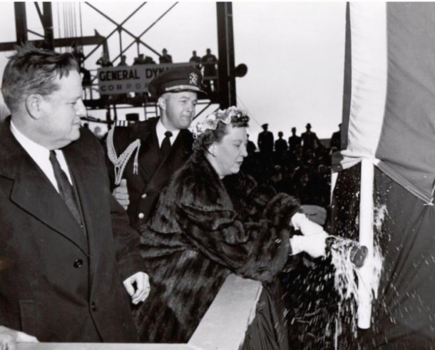 presidentsvrouw Mamie Eisenhouwer breekt een fles champagne over de boog van het schip