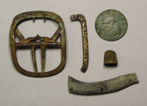 Various personal items from the Goodsell site: a plain brass shoe buckle, a fragment of a silver shoe buckle frame with a repair, a 1746 George II halfpenny, a child's small thimble, and part of a brass jackknife handle with a rococo design - AHS, Inc., Storrs
