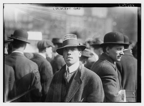Man wearing a hat with card stating "Bread or Revolution"