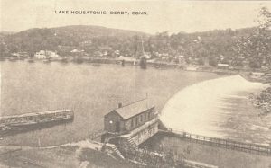 Postcard of a lake above a dam with hills on the far side of the river