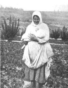 A woman standing in a field holding a child in her arms.