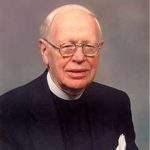 Portrait of an older man wearing a black suit and a white clerical collar. He is also wearing glasses and has a white handkerchief in his breast pocket