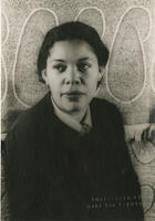 Black and white photograph of a woman from the chest up. She is facing the camera but looking away.