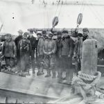 Eleven men standing on the deck of a ship