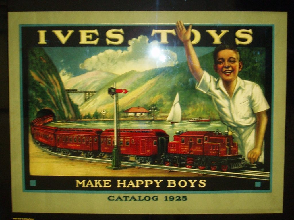 Image of an advertisement with a red train coming through a mountain and a boy in white clothing waving. There is a body of water next to the train with two boats. The tagline reads "Ives Toys Make Happy Boys." Catalog 1925