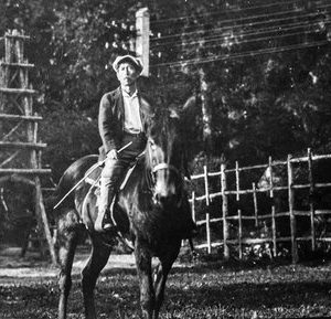 Man sitting on a donkey in front of a fence