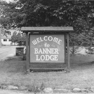 Wooden sign in front of a tree reading "welcome to Banner Lodge"