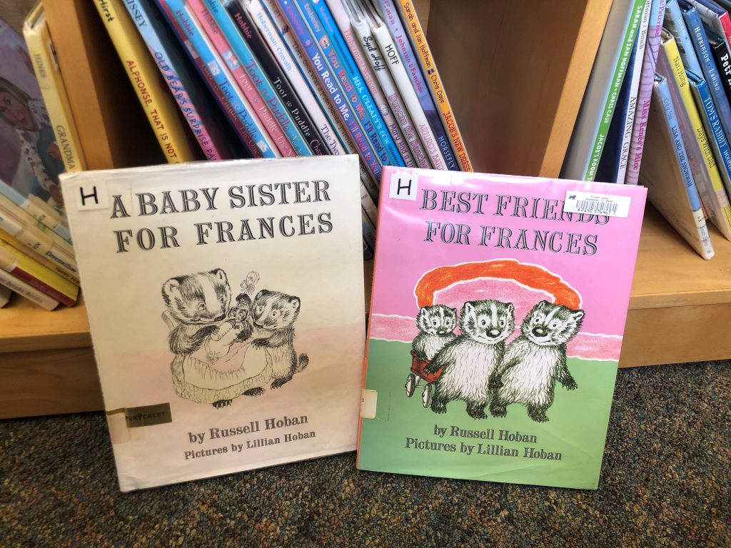 Two picture books propped up against a shelf that has more books