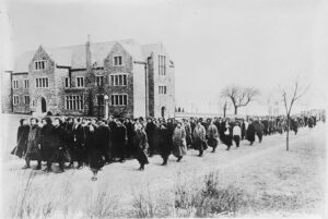 Large group of women walking past a large building in the winter