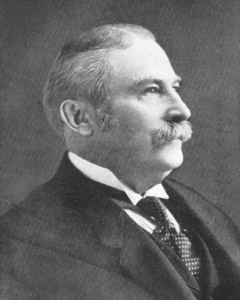 Side profile portrait of a man with short hair and a mustache.