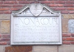 Stone plaque on the side of a brick wall that is titled "Linonia Court" with more text etched beneath