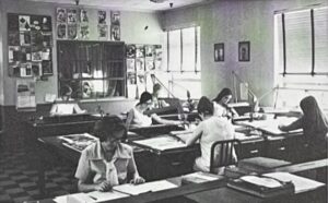 Numerous women sitting at desks in an open room