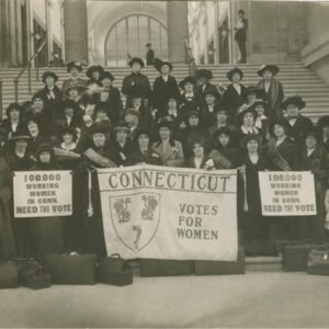 Group of women standing on steps holding banners about women's suffrage