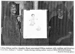 Newspaper scan of a photograph of two women standing next to an easel with paper and a drawing. There is a text caption beneath the picture